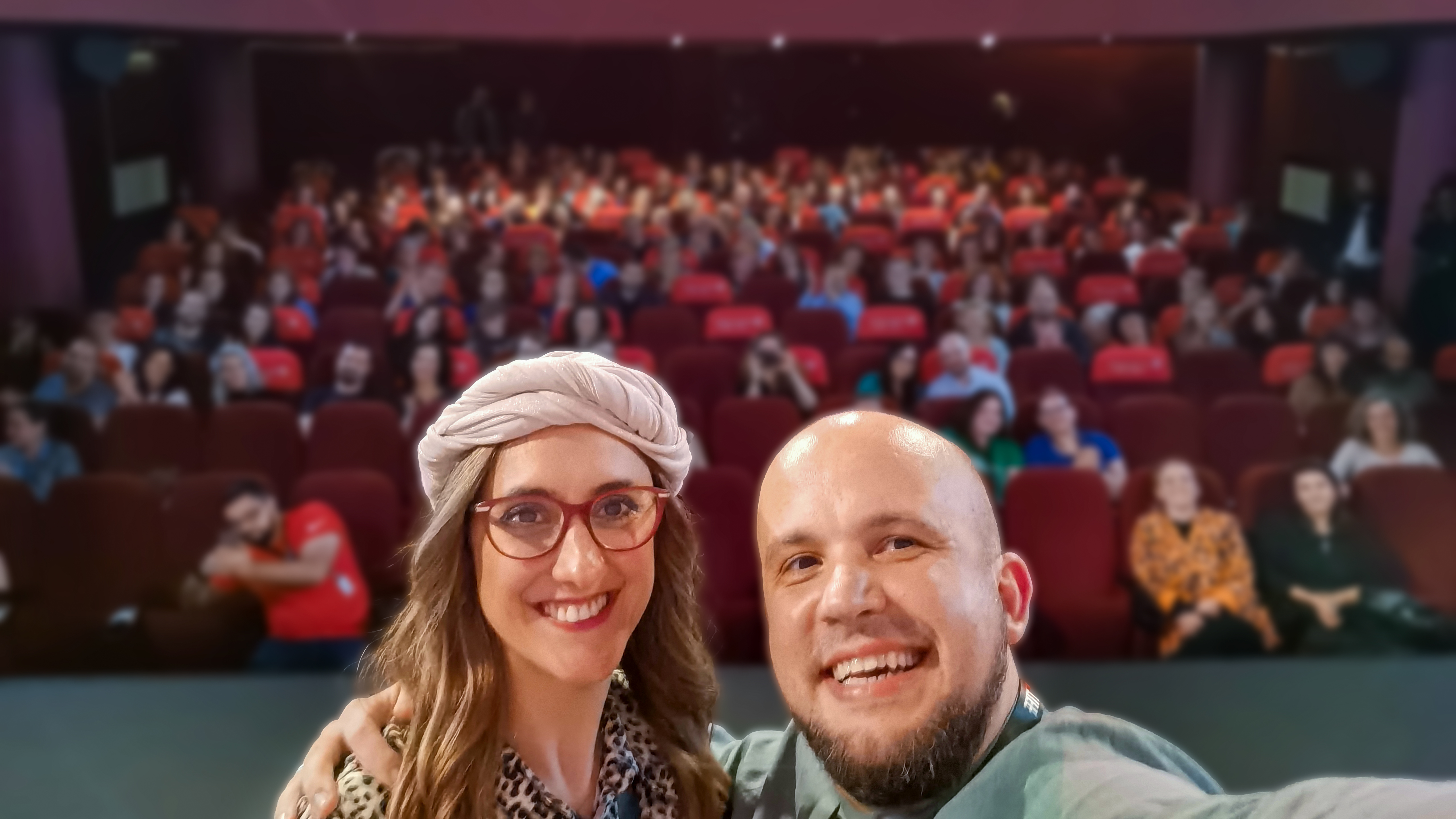 Daniel and Alexandra Bărnuți smiling in front of a full cinema hall